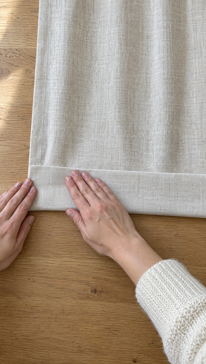 A palm pressing along a folded curtain hem