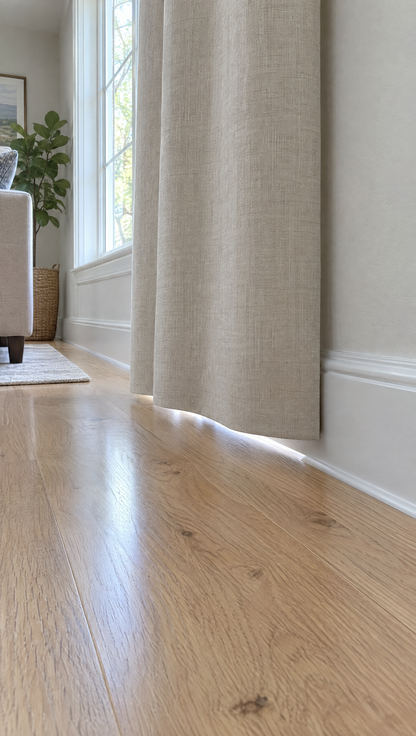 A curtain hem hanging straight just above a wooden floor