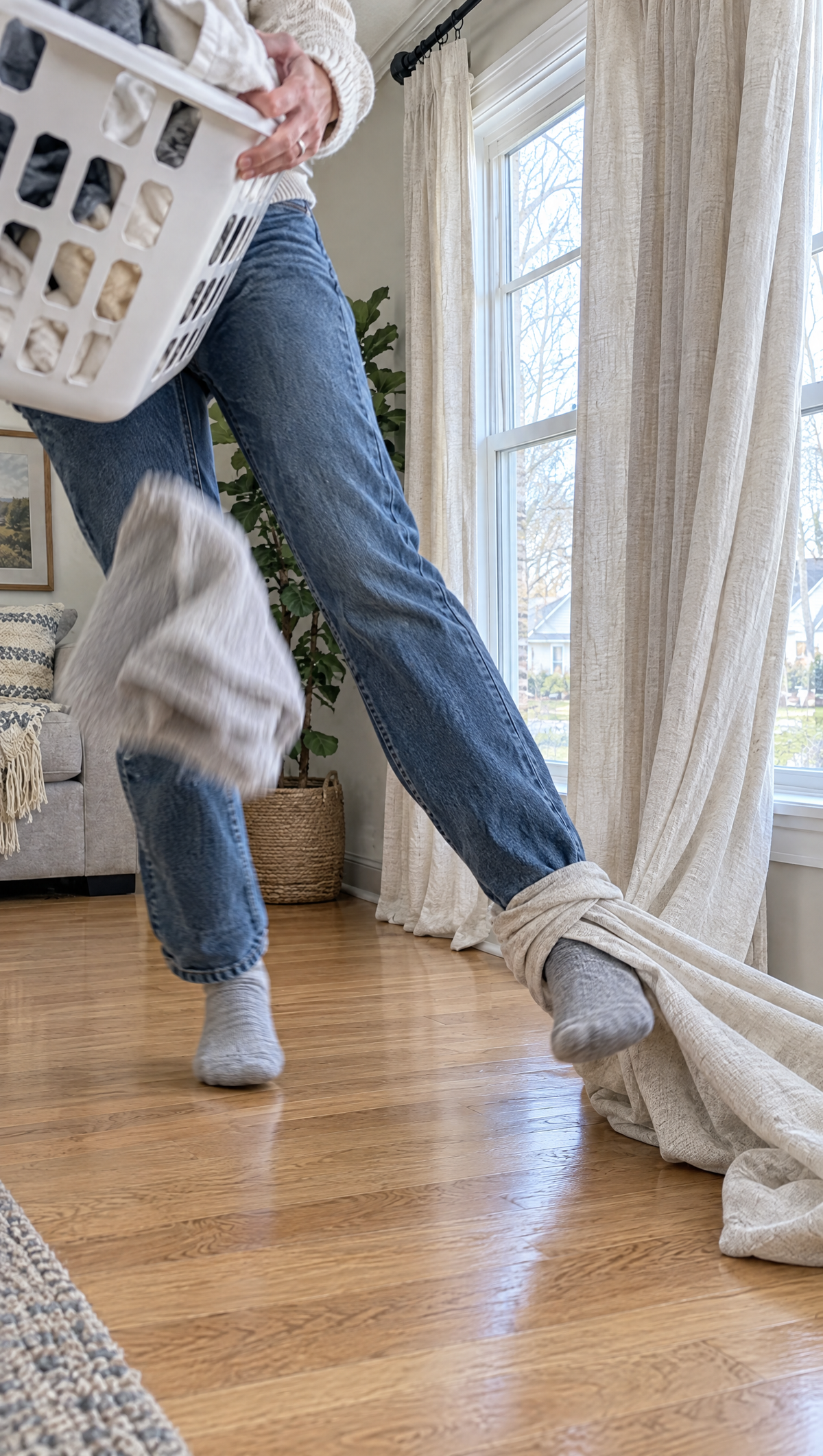 A foot caught in a curtain pooled on the floor while carrying a laundry basket